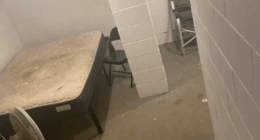 Basement room with mattress, fan, and chairs.