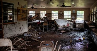 Muddy interior of a flood-damaged cabin with overturned furniture.
