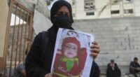 Esraa Abu Halib shows to journalists a photo of her 5-month-old baby, Zainab, who died from malnutrition-related causes, according to the family and the hospital, as she stands outside the Nasser Hospital, in Khan Younis, Gaza Strip, Saturday, July 26, 2025. (AP Photo/Mariam Dagga)