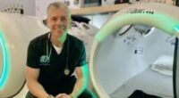 Therapist sitting in front of hyperbaric chambers.
