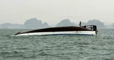 People stand on a tourist boat that capsized in Halong Bay on Saturday.