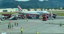 A Volotea airplane on a tarmac surrounded by emergency vehicles.