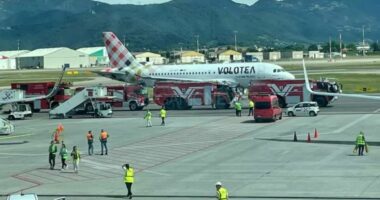 A Volotea airplane on a tarmac surrounded by emergency vehicles.