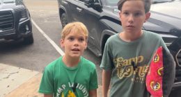 Two boys in Camp La Junta shirts stand outside.