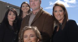 Group photo of five people, four women and one man, in front of a building.