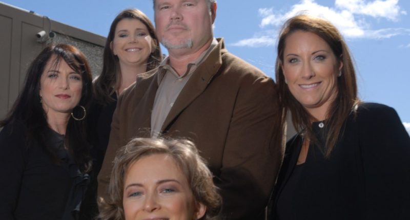 Group photo of five people, four women and one man, in front of a building.