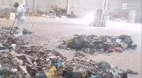 A worker in a protective suit cleans up a pile of garbage where a baby's remains were found.