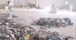 A worker in a protective suit cleans up a pile of garbage where a baby's remains were found.