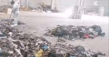 A worker in a protective suit cleans up a pile of garbage where a baby's remains were found.