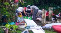 Two adults sweep through the belongings of campers in the aftermath of the flash flood