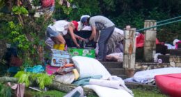 Two adults sweep through the belongings of campers in the aftermath of the flash flood