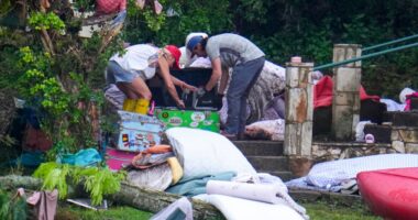 Two adults sweep through the belongings of campers in the aftermath of the flash flood