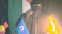 Disturbing bombing threat is issued on video by masked man standing with Aboriginal and Torres Strait Islander flags: 'Every colony will burn'
