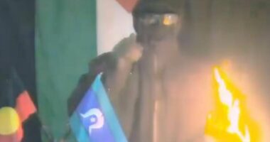 Disturbing bombing threat is issued on video by masked man standing with Aboriginal and Torres Strait Islander flags: 'Every colony will burn'