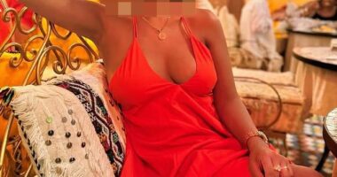 Woman in orange dress with face blurred.