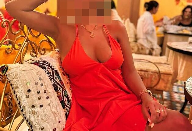 Woman in orange dress with face blurred.