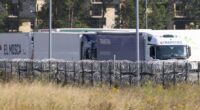Trucks behind razor wire.