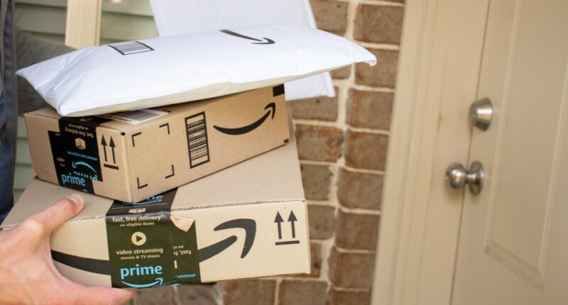 Person holding Amazon Prime packages at a front door.