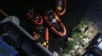 Search and rescue teams in inflatable boats at night.