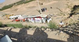 Bus crash scene with rescue workers.