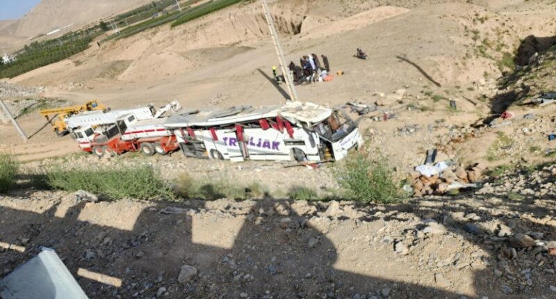 Bus crash scene with rescue workers.