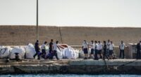 Coast guard officers carrying a body bag on a dock.