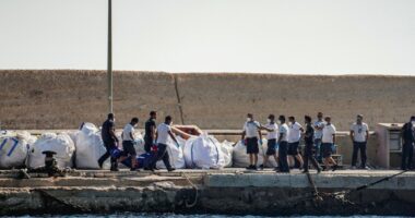 Coast guard officers carrying a body bag on a dock.