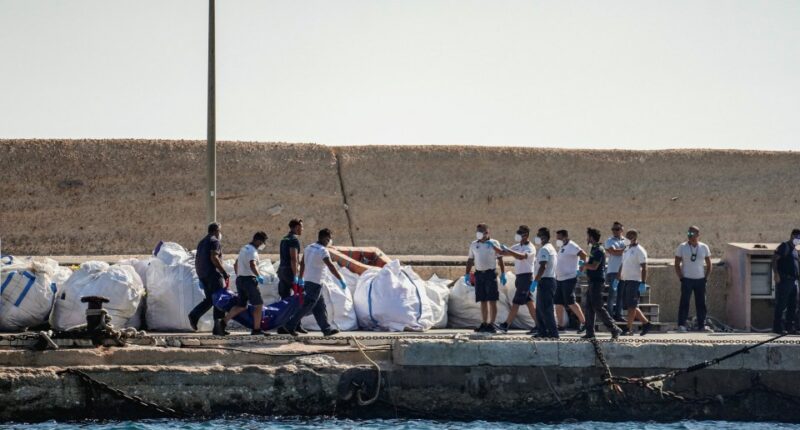 Coast guard officers carrying a body bag on a dock.