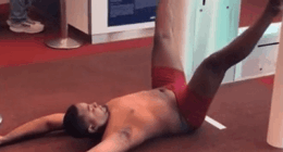 Man in red underwear lying on the floor at an airport gate.
