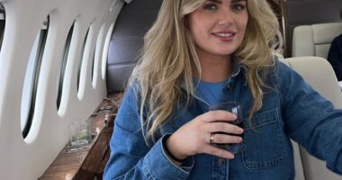 Woman seated in a private jet with two men in the background.