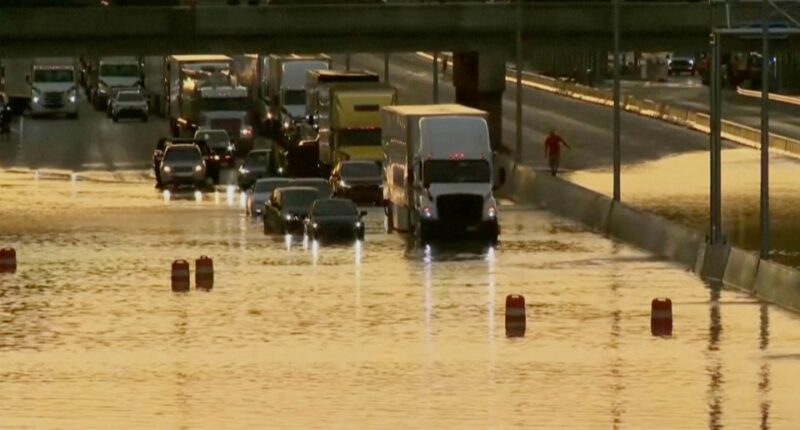 Flooded road with vehicles driving through.
