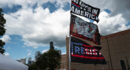 Bernie Sanders signs flying in foreground, Chicago skyscrapers in the background amid clouds