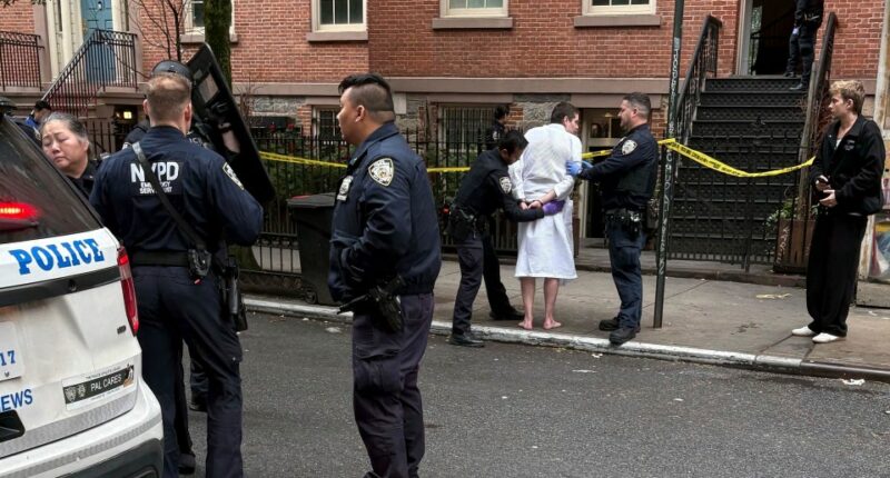 Police officers arresting a man in a bathrobe.
