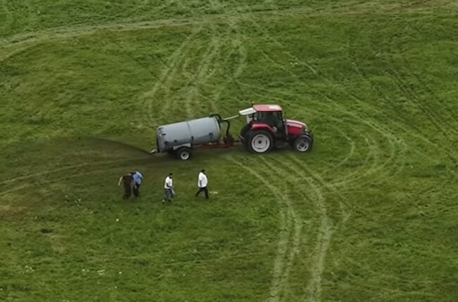 Tractor spreading manure on a field.