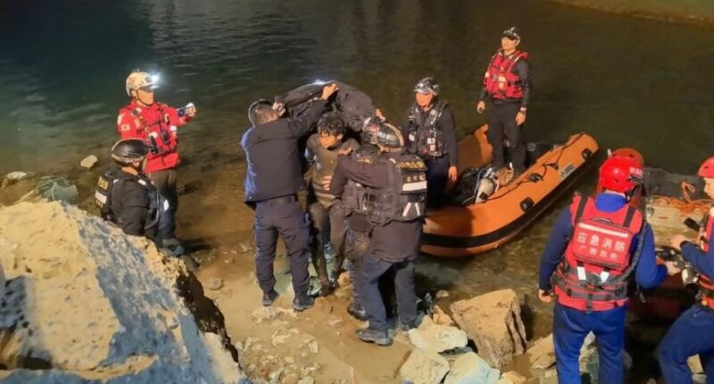 Rescue workers assisting a diver near a body of water.