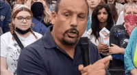 Man speaking into microphone at a protest.