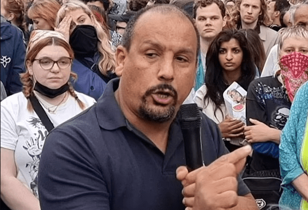 Man speaking into microphone at a protest.
