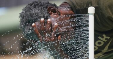 Paul Williams cools off in water while taking a break from yard work in Richardson, Texas, July 31, 2025. (AP Photo/LM Otero, File)