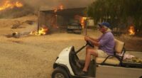 A resident rides a golf cart as he exits his property while the Canyon Fire burns in Hasley Canyon, California.