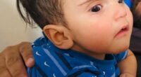 Photo of a baby in a blue shirt.