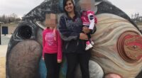 A woman and two children posing in front of a playground mural depicting planets.