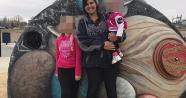 A woman and two children posing in front of a playground mural depicting planets.