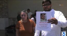 Couple holding a missing child poster.