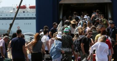 Passengers waiting at a ferry terminal with luggage.