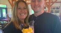 Woman and man posing for a photo, woman holding yellow roses.