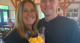 Woman and man posing for a photo, woman holding yellow roses.