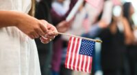 Person holding a small American flag at a naturalization ceremony.