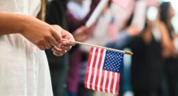 Person holding a small American flag at a naturalization ceremony.