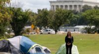 Woman stands in front of tents with the Lincoln Memorial in the background.