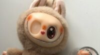 Tan plush toy with bunny ears and a quirky face.